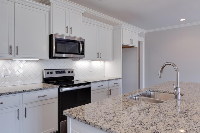kitchen featuring appliances with stainless steel finishes, a sink, white cabinetry, light stone countertops, and ornamental molding