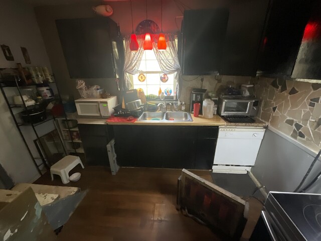 kitchen with white appliances, a sink, wood finished floors, and decorative backsplash
