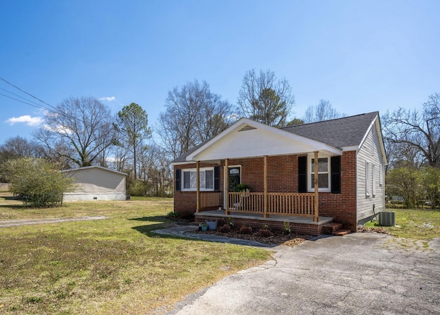 view of front of house featuring a porch, a front lawn, brick siding, roof with shingles, and cooling unit