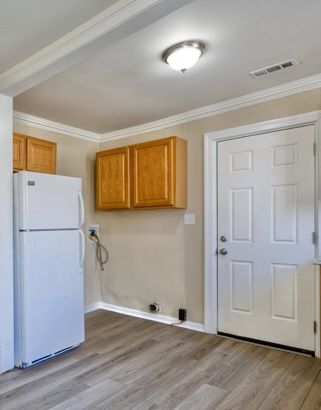 washroom with hookup for a washing machine, cabinet space, crown molding, light wood-type flooring, and baseboards