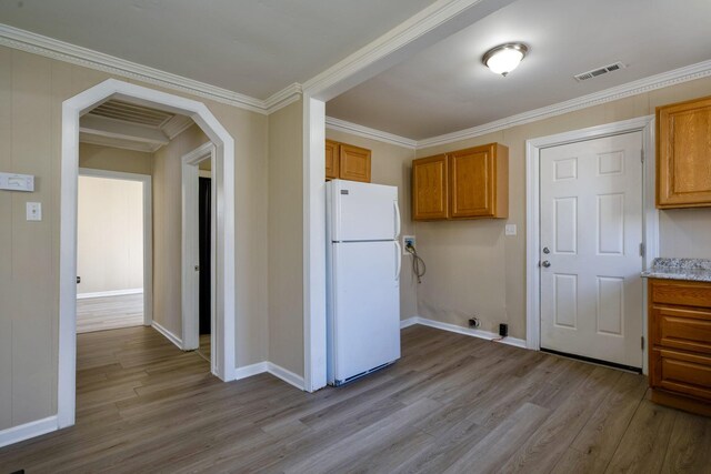 kitchen with freestanding refrigerator, wood finished floors, baseboards, arched walkways, and brown cabinets