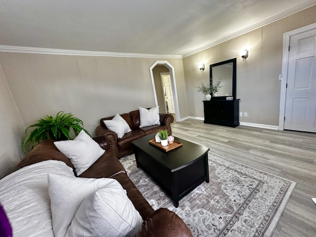 living room featuring light wood-type flooring, arched walkways, ornamental molding, and baseboards