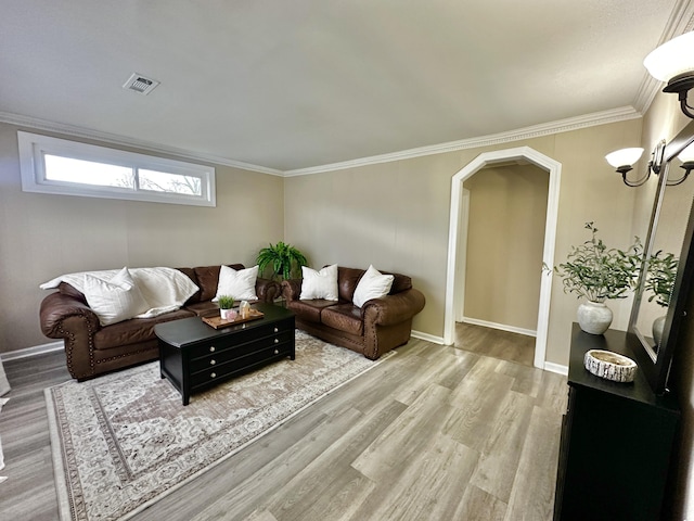 living room with wood finished floors, ornamental molding, baseboards, a chandelier, and arched walkways