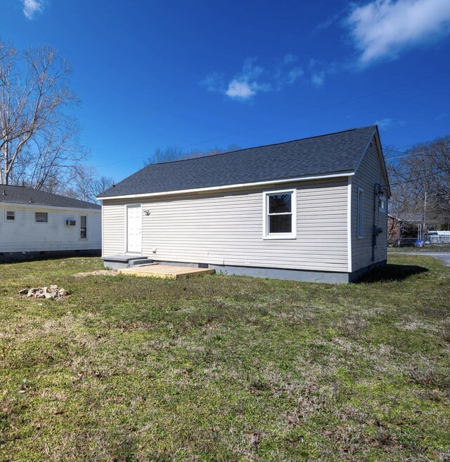 back of property with a lawn and roof with shingles
