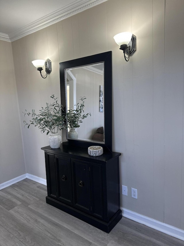 detailed view of wood finished floors, ornamental molding, baseboards, and a decorative wall