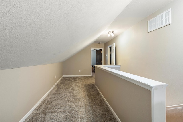 corridor with carpet flooring, lofted ceiling, an upstairs landing, baseboards, and a textured ceiling
