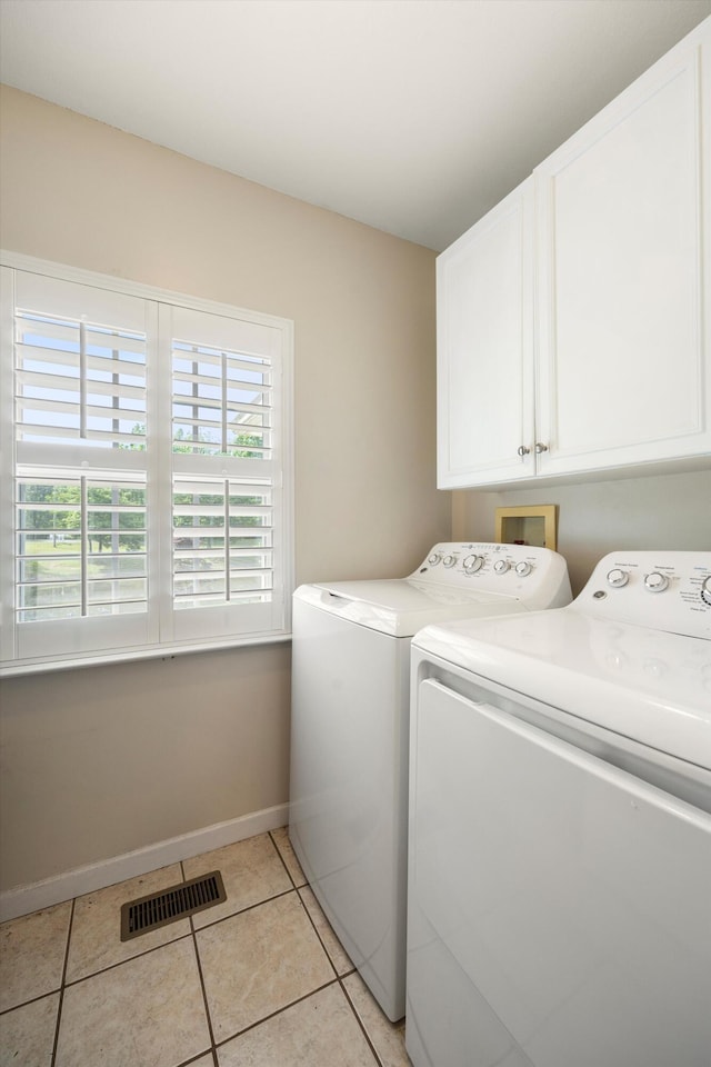 laundry area with cabinet space, washing machine and dryer, baseboards, and light tile patterned flooring
