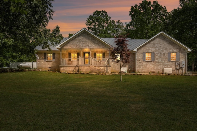 rear view of property with brick siding, covered porch, a yard, and crawl space