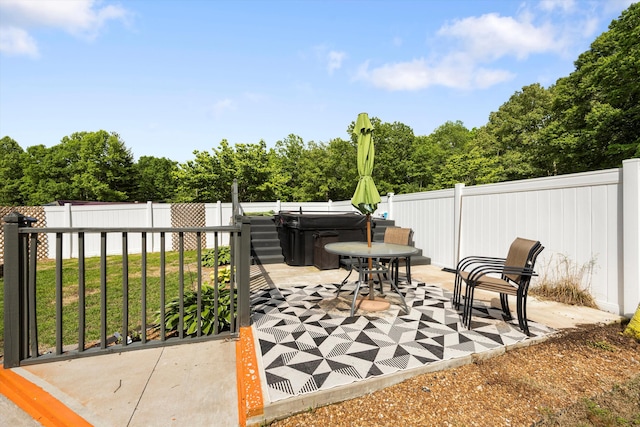 view of patio / terrace with a hot tub, a fenced backyard, and view of scattered trees