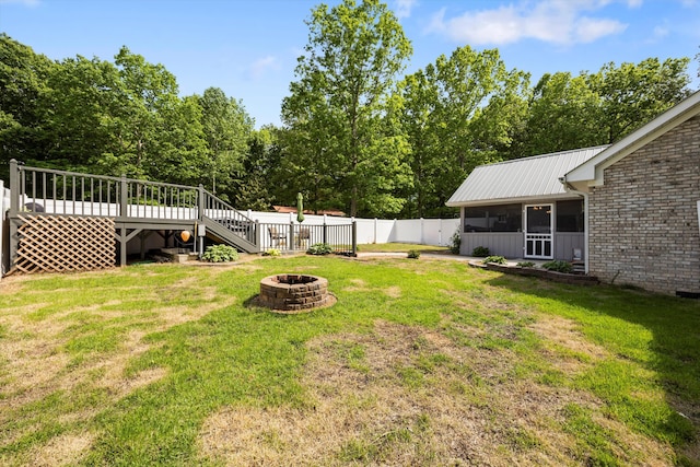 view of yard with a fire pit, a wooden deck, a sunroom, and stairway