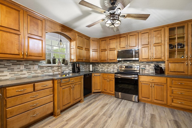 kitchen featuring appliances with stainless steel finishes, a sink, brown cabinetry, and a ceiling fan