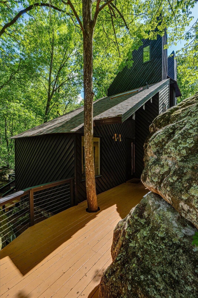 view of side of home featuring a deck and a shingled roof