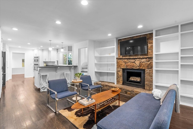 living room with dark wood-style flooring, recessed lighting, a stone fireplace, baseboards, and built in features