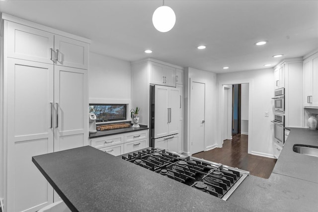 kitchen with paneled refrigerator, stovetop, recessed lighting, dark countertops, and white cabinets