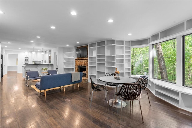 dining room featuring recessed lighting, dark wood-style flooring, a fireplace, and built in shelves
