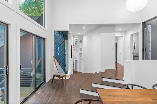 dining room featuring wood finished floors, recessed lighting, stairs, and a high ceiling