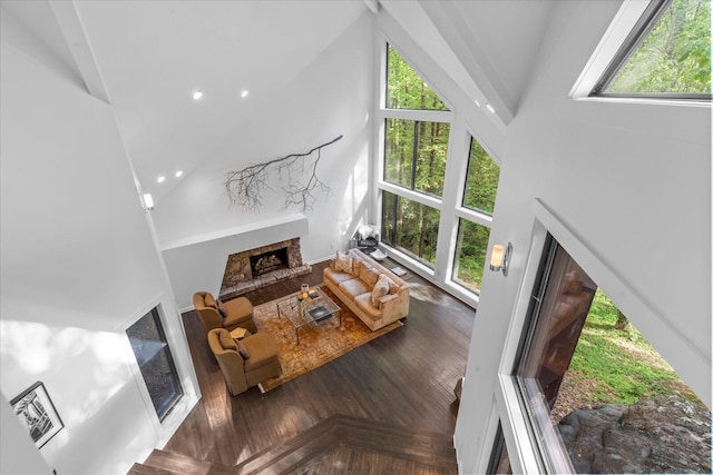 living area featuring high vaulted ceiling, a fireplace with raised hearth, and recessed lighting