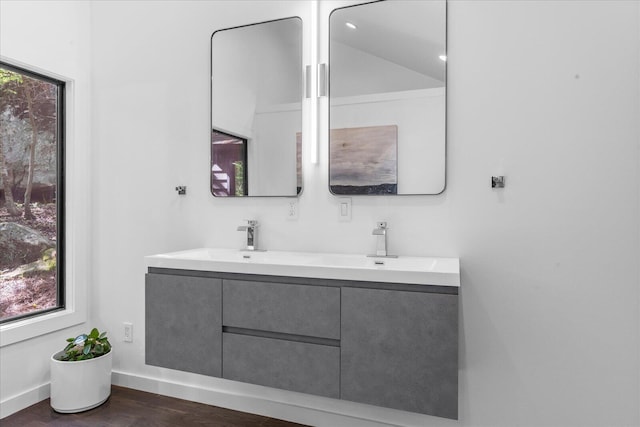 full bathroom with wood finished floors, double vanity, and baseboards