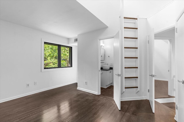 unfurnished bedroom with wood finished floors, baseboards, and ensuite bath