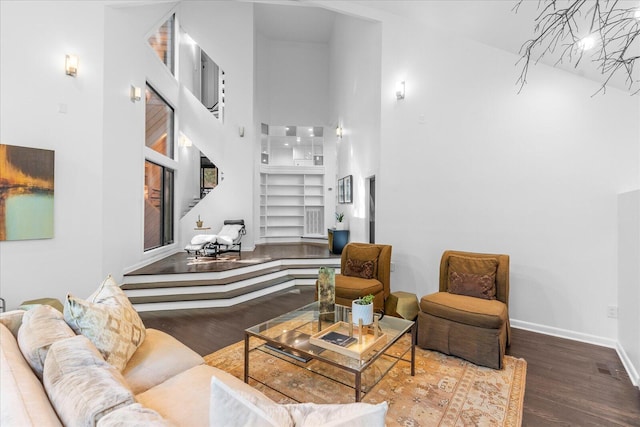 living area featuring a towering ceiling, wood finished floors, and baseboards