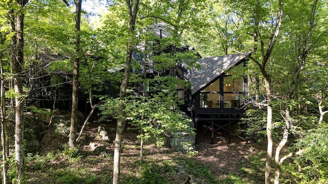view of property exterior featuring roof with shingles and a deck