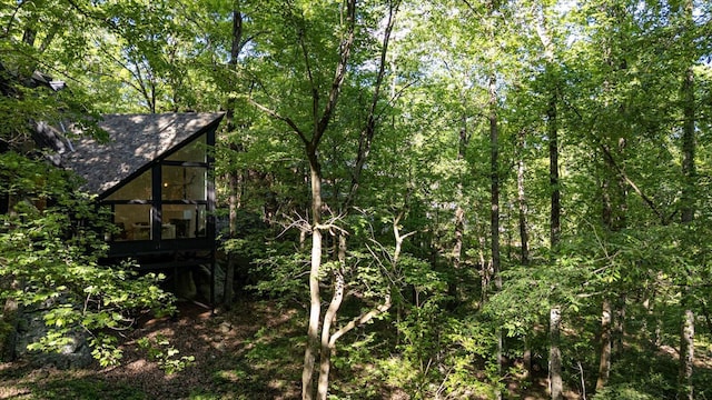 view of property exterior featuring a shingled roof and a sunroom