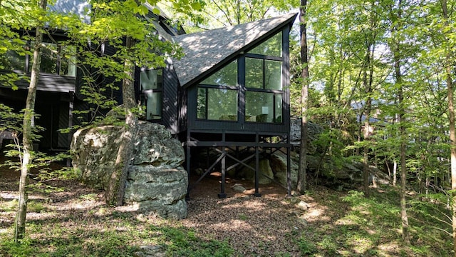 rear view of house featuring a shingled roof and a sunroom