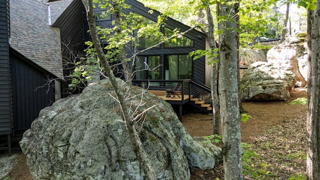 view of home's exterior featuring a shingled roof, a wooden deck, and stairs
