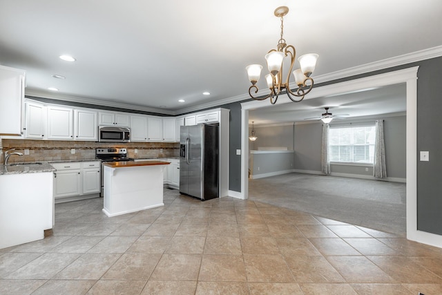 kitchen featuring appliances with stainless steel finishes, ornamental molding, a chandelier, baseboards, and backsplash