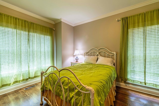 bedroom featuring wood finished floors, crown molding, and baseboards