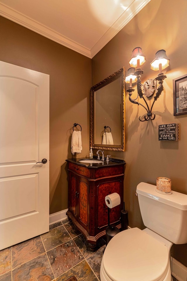 half bath with ornamental molding, toilet, stone tile floors, vanity, and baseboards