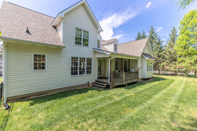 back of house with a shingled roof, a yard, and a wooden deck
