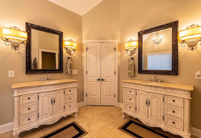 full bath with two vanities, vaulted ceiling, and baseboards