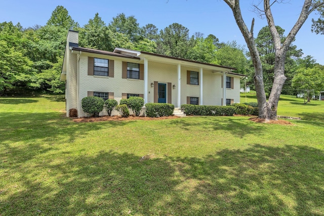 bi-level home featuring a chimney, brick siding, and a front yard