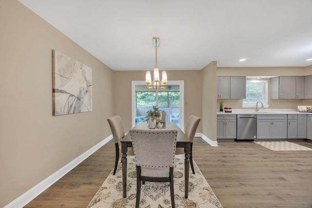dining room featuring a chandelier, baseboards, wood finished floors, and recessed lighting