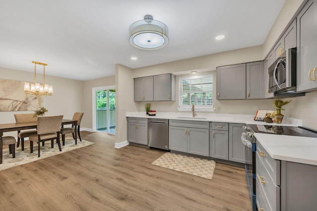 kitchen with appliances with stainless steel finishes, gray cabinets, light countertops, light wood finished floors, and recessed lighting
