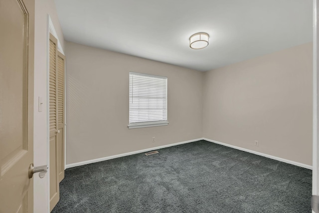 unfurnished bedroom featuring dark colored carpet, baseboards, and a closet