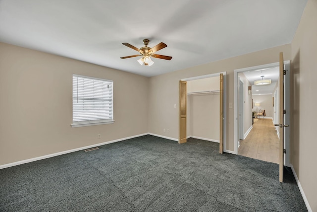 unfurnished bedroom featuring attic access, dark carpet, baseboards, and a closet