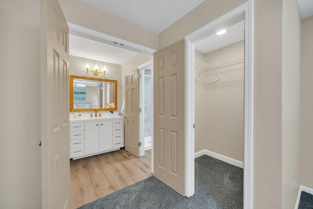 bathroom featuring a spacious closet, vanity, a chandelier, baseboards, and wood finished floors