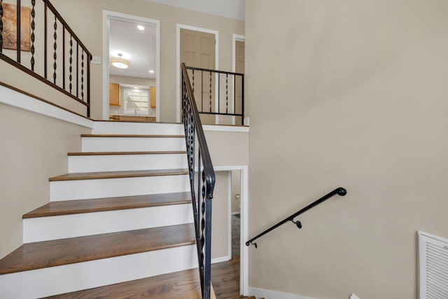 staircase with wood finished floors and recessed lighting
