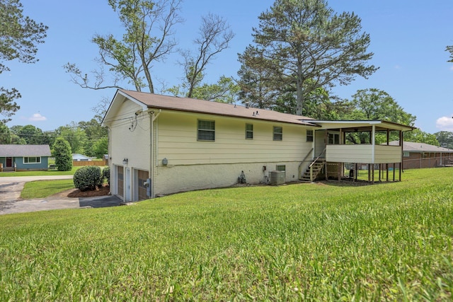 back of house with asphalt driveway, a sunroom, a garage, stairway, and a yard