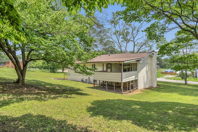 back of property featuring a yard, a chimney, and central AC unit