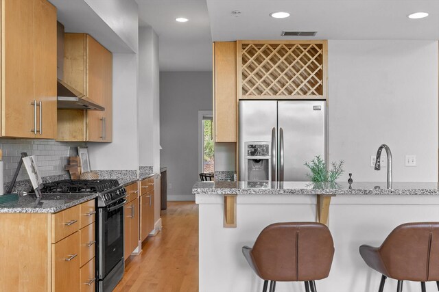 623 Hamilton Ave, Chattanooga, TN 37405 - kitchen featuring stainless steel refrigerator with ice dispenser, range with gas cooktop, a breakfast bar, light stone countertops, and light wood-type flooring