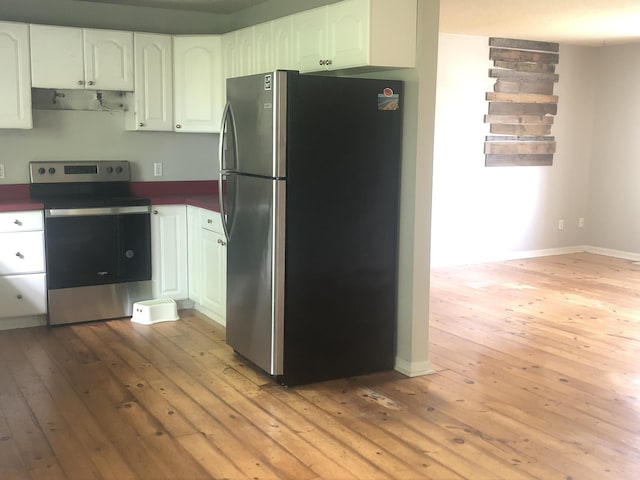 kitchen with appliances with stainless steel finishes, light wood-style flooring, dark countertops, white cabinets, and baseboards