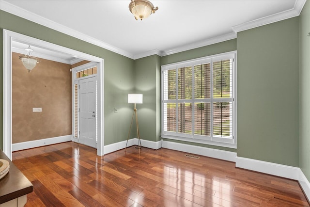 spare room with wood-type flooring, plenty of natural light, baseboards, and crown molding