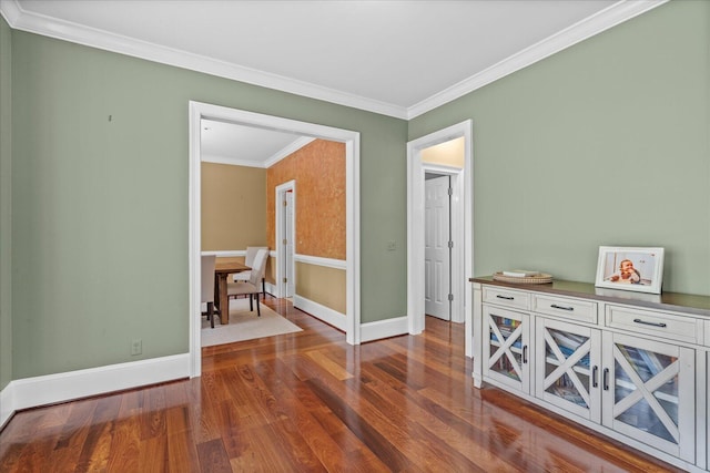 spare room with dark wood-style floors, crown molding, and baseboards
