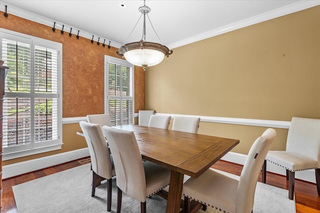 dining space featuring wood finished floors, plenty of natural light, baseboards, and ornamental molding