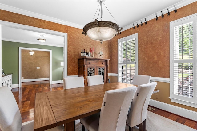 dining area with wood finished floors, baseboards, ornamental molding, and a chandelier