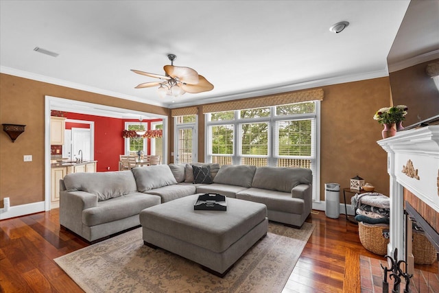 living room featuring ceiling fan, dark wood-type flooring, crown molding, a fireplace with flush hearth, and baseboards