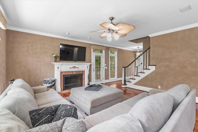living area featuring wood finished floors, baseboards, a ceiling fan, stairs, and ornamental molding
